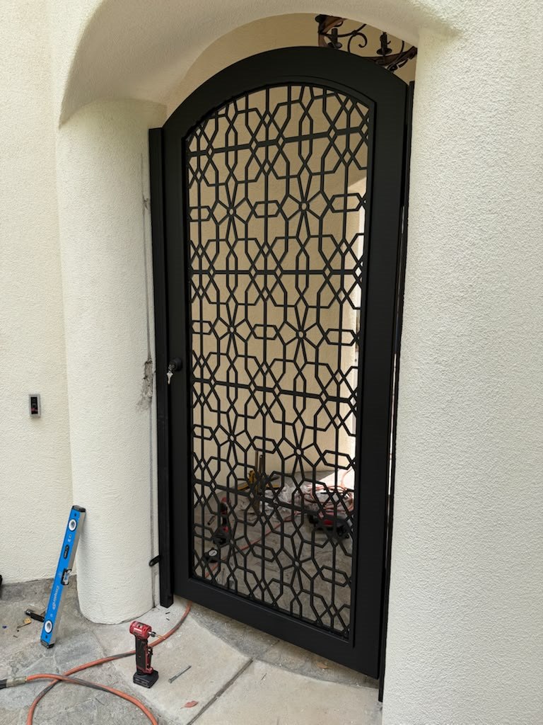 Arched iron gate with geometric lattice during installation