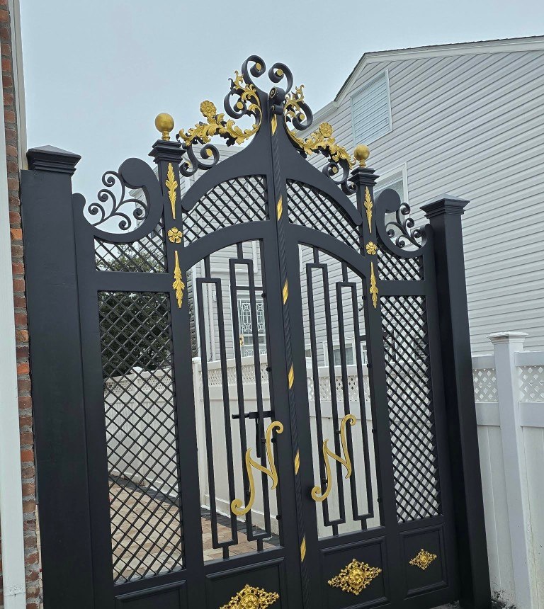 Ornate black iron driveway gate with gold scrollwork