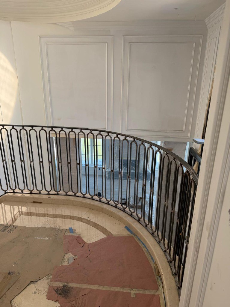 Curved iron landing railing with oval loop balusters