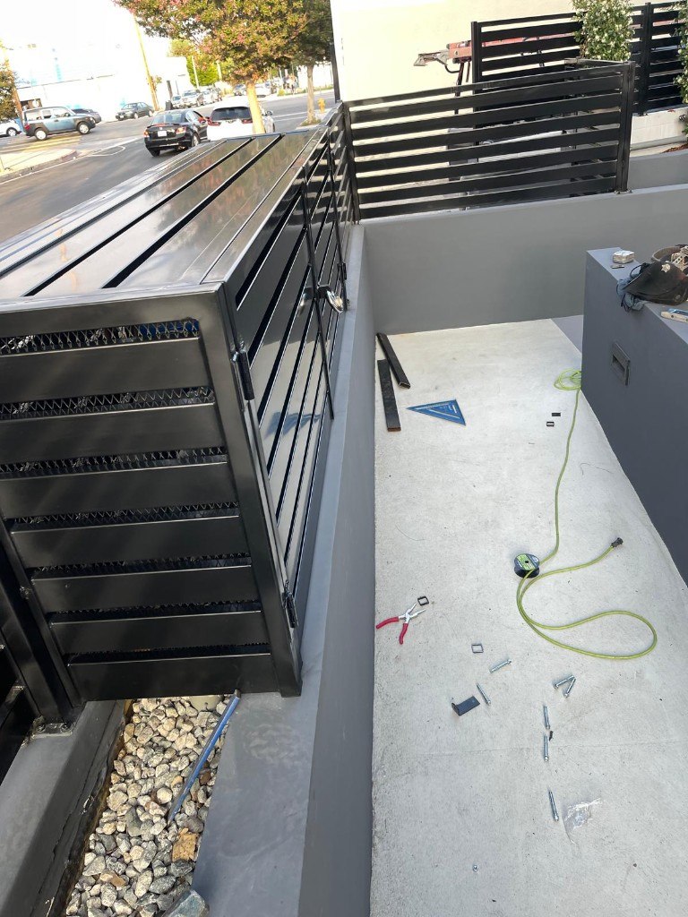 Black horizontal-slat steel enclosure during installation