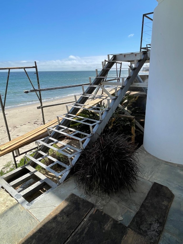 Steel stair frame beside a coastal building and the ocean