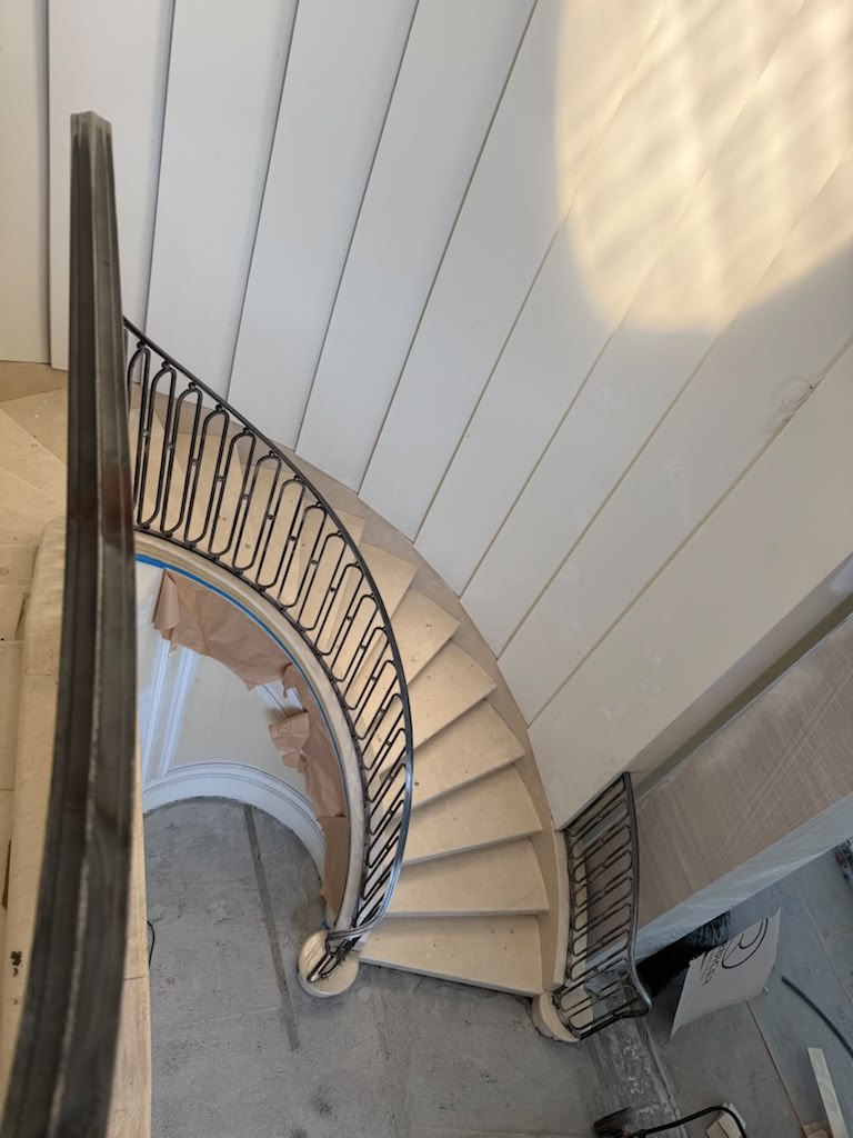Curved stone staircase with custom iron railing