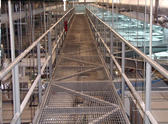 Industrial steel catwalk with bar grating and pipe railings in a commercial facility